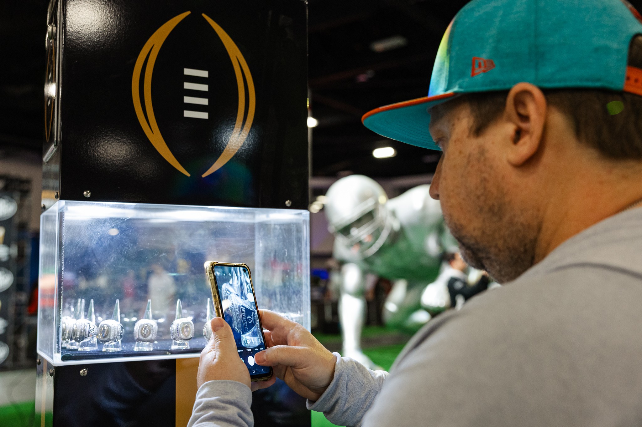 Fan photographing College Football Playoff memorabilia at Fan Central in Miami Beach
