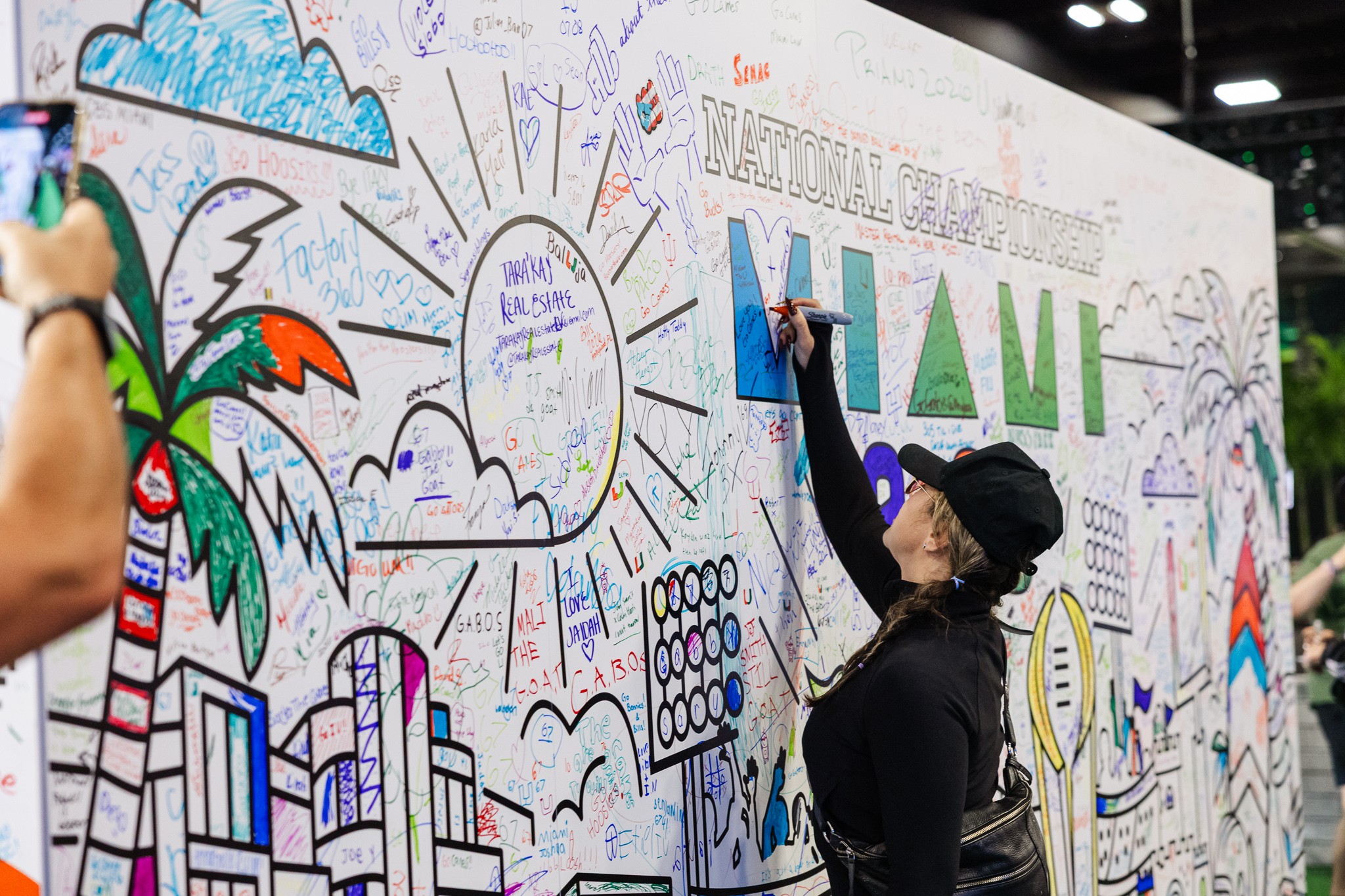 Fans signing an interactive National Championship wall at College Football Playoff Fan Central